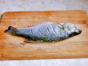 放在砧板上，鱼身两面各划四刀。