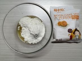把玉米油和糖浆倒入盆中，搅拌均匀，倒入广式月饼预拌粉