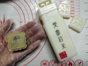 把饼皮慢慢向上推，收口捏紧，在面粉中滚一圈防粘（低中高粉都可以），把多余的粉拍掉，搓成圆柱形，方便入模。放入模具中，向下按压，提起模具，月饼胚就做好了。在月饼上方用喷壶喷水雾，不是对着月饼喷