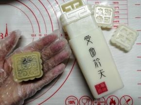 把饼皮慢慢向上推，收口捏紧，在面粉中滚一圈防粘（低中高粉都可以），把多余的粉拍掉，搓成圆柱形，方便入模。放入模具中，向下按压，提起模具，月饼胚就做好了。在月饼上方用喷壶喷水雾，不是对着月饼喷