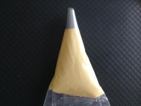 步骤17、将面糊装入裱花袋，此时可以预热烤箱上下230预热。用刮板将面糊推到裱花袋前端。