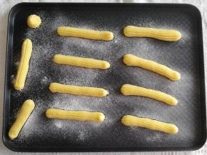 步骤18、然后在烤盘上，裱花嘴离高一些，水平移动，挤出一长条面糊，大概12公分的样子。收尾往下按压再提起。我挤的比较随性，有强迫症的小伙伴，可以挤直线！然后用手指蘸一些水，将尾部翘起的面糊轻轻压平。筛上一层糖粉，让泡芙表面更酥脆，膨胀均匀。