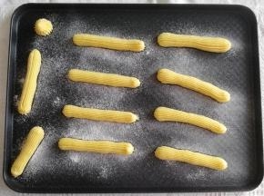 步骤18、然后在烤盘上，裱花嘴离高一些，水平移动，挤出一长条面糊，大概12公分的样子。收尾往下按压再提起。我挤的比较随性，有强迫症的小伙伴，可以挤直线！然后用手指蘸一些水，将尾部翘起的面糊轻轻压平。筛上一层糖粉，让泡芙表面更酥脆，膨胀均匀。