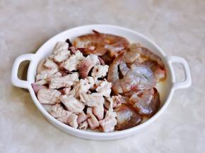 鱿鱼与虾尾放入盘中，加入一勺料酒抓拌均匀，腌制10分钟。