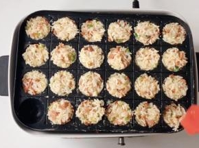把拌好的米饭填入章鱼烧盘，压实，用中火煎。
