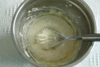 步骤5、软化到能用刮刀轻易抹开的黄油，用蛋抽打顺滑，加糖粉（如有结块需过筛），搅打至微微变白。分次加入常温全蛋液，搅打顺滑。再倒入所有椰蓉和奶粉。