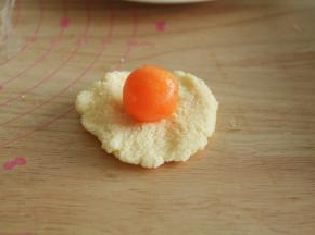 步骤13、然后将冷藏好的椰蓉馅取出，30克一个，按扁，包上蛋黄备用。