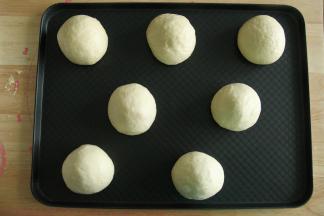 步骤15、左手按住馅料球，右手往上推，收口收紧，收口朝下放置在烤盘上。