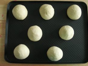 步骤15、左手按住馅料球，右手往上推，收口收紧，收口朝下放置在烤盘上。