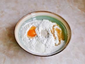 首先将面粉放入大口器具中，中间挖个坑加入酵母，旁边加入玉米油，白砂糖，鸡蛋，搅拌均匀，再分次加入温水，搅拌成絮状。