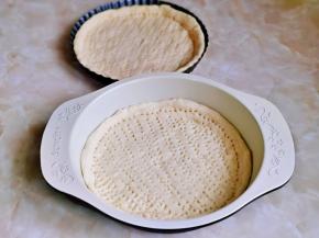 取一块面团，用擀面杖擀出圆饼，与自己的披萨盘一样大小就可以，用食品叉扎出不规则的洞洞眼。