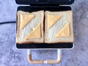 在吐司片上放上切好的芝士片，角对角，边对边放好，留出边缘，因为我用的是三角烤盘，所以切开放啦！
