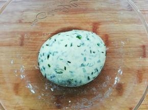 韭菜出水后加入面粉揉成稍微硬点的面团，盖上盖子醒面15分钟。