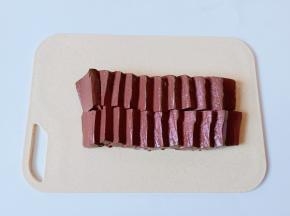 把鸭血放在案板上，横着切一下再切成小块。