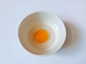 把一个鸡蛋嗑入碗里。
