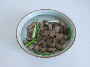 花蛤里面加一点葱段，盐经过浸泡可以去除泥沙。