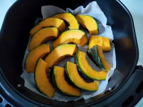 空气炸锅的炸篮垫一张油纸，铺好南瓜。