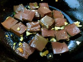 锅中倒入底油加热放入蒜粒爆香再放入鸭血大火爆炒