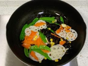 倒入胡萝卜、玉米、黑木耳、藕片和荷兰豆翻炒片刻。