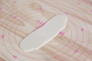 把面团擀成长舌状，卷起来，盖住保鲜膜松弛15分钟后，再次擀成长舌状。