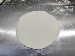 案板上洒一层薄薄的干粉防粘，取一个小面团压扁，然后用擀面杖擀成圆形，和饺子皮一样中间厚边缘薄。实在擀不圆也没关系。