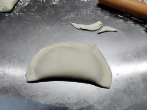 将面皮另一半盖上，边缘捏紧。看到边上的废料没，面皮擀不圆没关系，把多余的边角剪掉就行了。