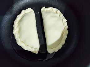 不粘锅放少量油，中小火加热，放入韭菜盒子开始煎。