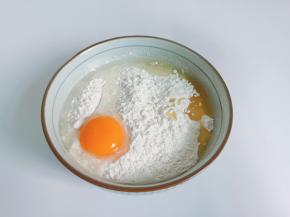 把高筋面粉放入碗里，加入鸡蛋、玉米油、盐。