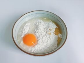把高筋面粉放入碗里，加入鸡蛋、玉米油、盐。