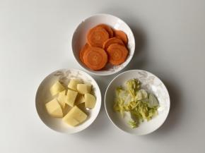 把土豆和胡萝卜切成小块，娃娃菜焯好之后，稍微放到不烫手的程度，再把娃娃菜的水分挤出来，如果水分太多，会让虾丸变得太稀，不容易成型。