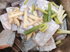 沥干水的带鱼加入姜丝，料酒和葱白段