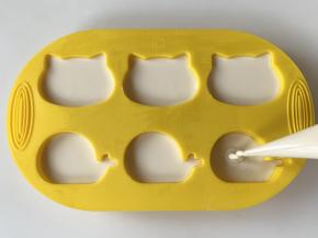 在裱花袋底部剪一个口，把面糊挤入模具中。