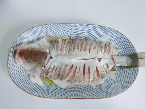 切好的海鲈鱼码在盘上，下面垫上葱段生姜片。