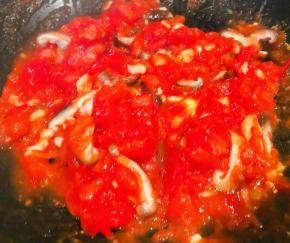 另起锅倒入少许底油加热放入蒜粒爆香再放入西红柿炒出汤汁再放入香菇炒匀