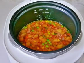 再把炒好的土豆腊肠倒入电饭煲内胆中铺平，内胆放回主机。