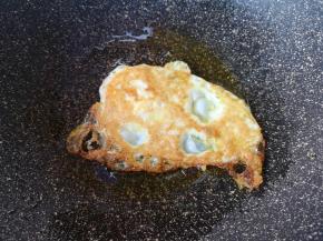 等到鸡蛋一面定型变成焦黄色以后，翻面煎另一面。