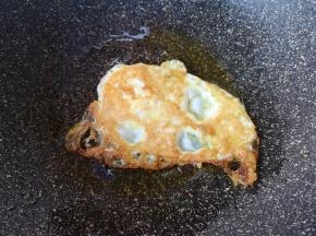 等到鸡蛋一面定型变成焦黄色以后，翻面煎另一面。