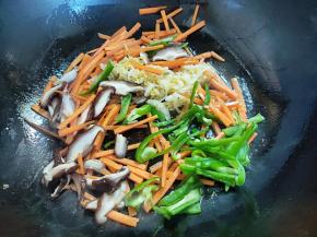 倒入胡萝卜、辣椒、香菇和酸菜煸炒一会，炒熟盛起。