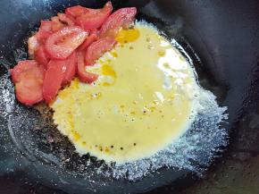 将番茄推一边，倒入蛋液。