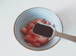 切好的猪肉丝放在碗里加生抽一勺。