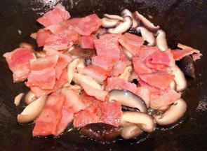 锅中放入底油加热放入培根炒出香味再放入香菇炒匀