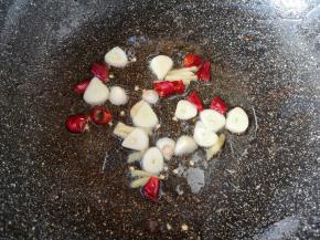 炒锅内继续倒油烧热，下入蒜片、姜丝和干红辣椒炒香。