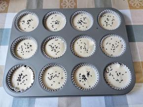 将蛋糕糊分装到模具中。蛋糕糊分装可以用勺子，注意舀的时候不要乱搅，以免消泡，也可以用裱花袋。表面再撒一些熟黑芝麻。