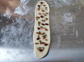 取一个卷，封口朝下，先用手压扁一下，然后擀成长条，注意宽度不能大过吐司盒的宽度，长度不超过40厘米为好，然后均匀撒上葡萄干。因为还有一点南瓜子仁要消耗掉，所以我又加了一点南瓜子仁，这个没有可以不加，或者加一点其它坚果。