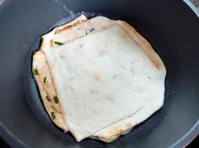 平底不粘锅刷一层油，然后将擀好的饼铺上，中小火开始煎。
