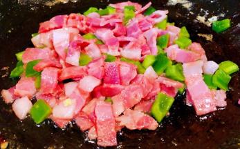 另起锅倒入底油加热放入培根炒出香味再放入青椒炒至断生