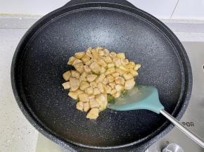 锅里热油，下入腌好的鸡肉丁炒至变白。