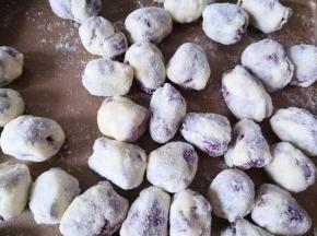 戴上手套逐个将红枣裹上糖，搓圆，撒奶粉，防粘