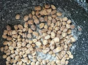 关火后放入花生米翻炒，随着温度降低花生米会挂满糖霜。