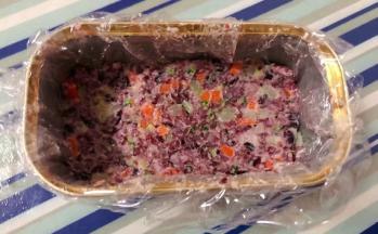 保鲜膜先放入午餐肉盒中再取适量拌好的时蔬双米饭压实